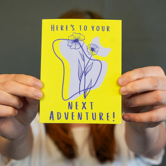 Flowers with a green background, with the wording Here's to your next adventure. 

